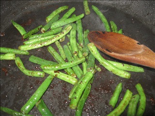 Add drained green beans and onions to a hot frying pan and stir until beans and onions are tender.